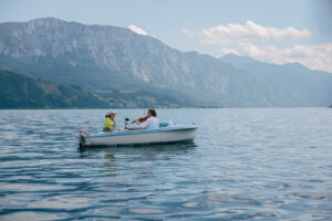 Zwei Musikerinnen auf einem Boot am Attersee mit blick auf die Berge.