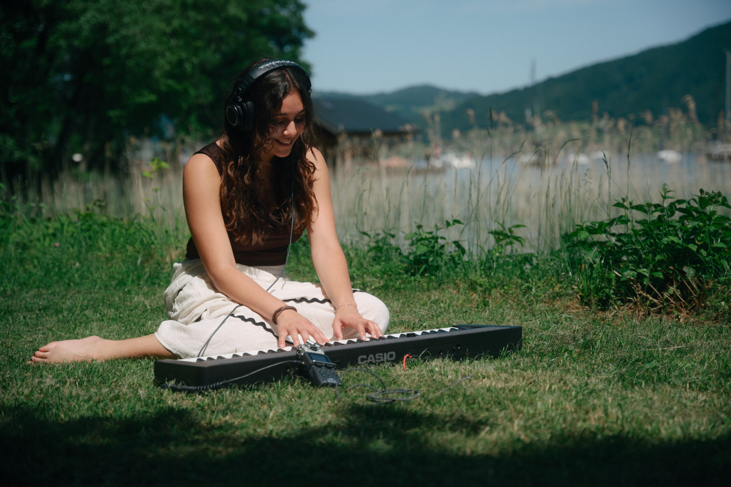 Eine Musikerin spielt Klavier auf einer Wiese am Ufer der Attersees.