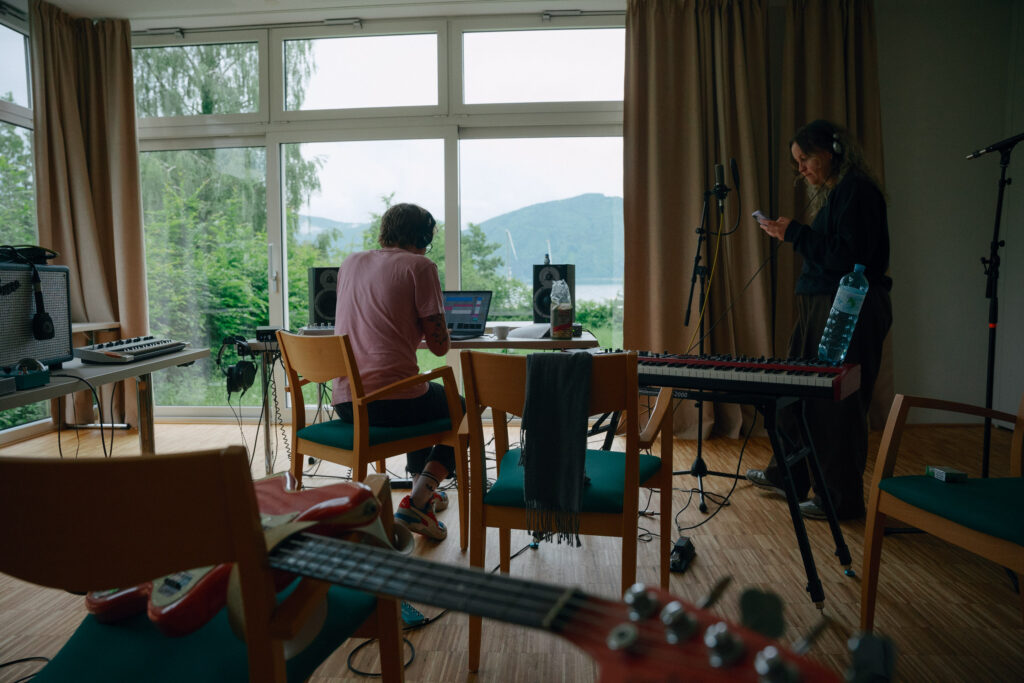 Foto von Künstler vor dem Laptop in Studio Setup in Zimmer mit Blick auf den See.