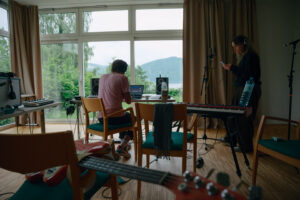 Foto von Künstler vor dem Laptop in Studio Setup in Zimmer mit Blick auf den See.