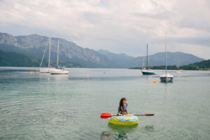 Foto von einer Person auf einem Paddelboot am See.