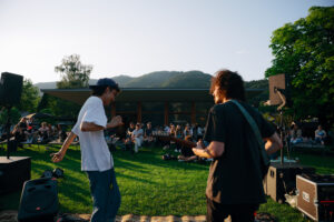 Künstler Lukas Oscar performt vor dem See und zahlreichem Publikum.